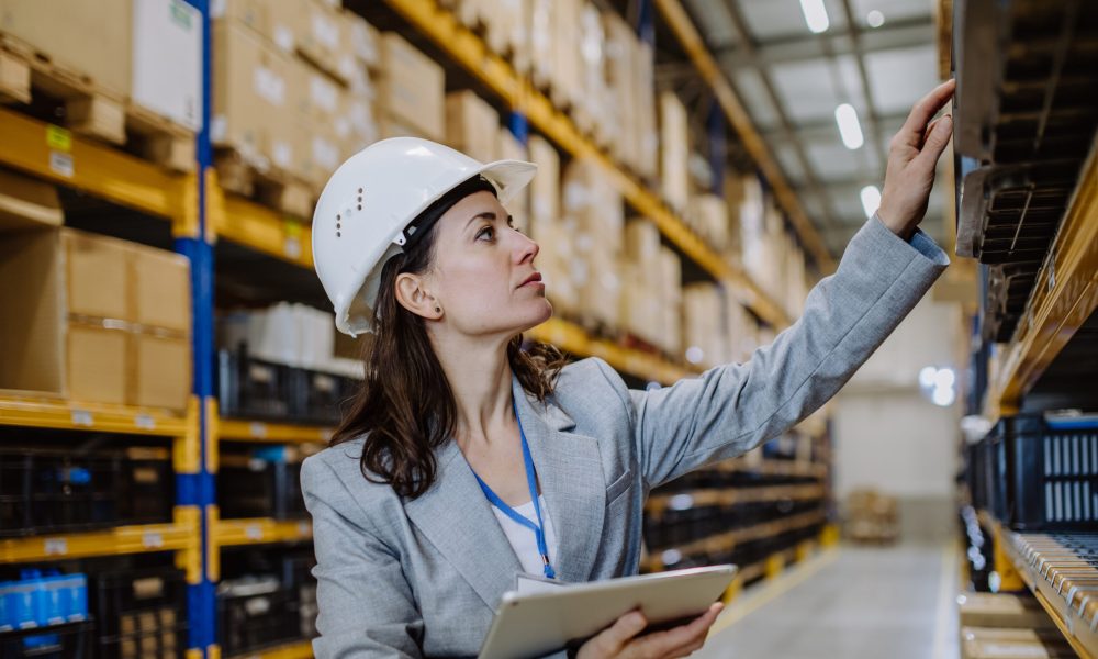 Manager woman in suit controlling goods in warehouse.
