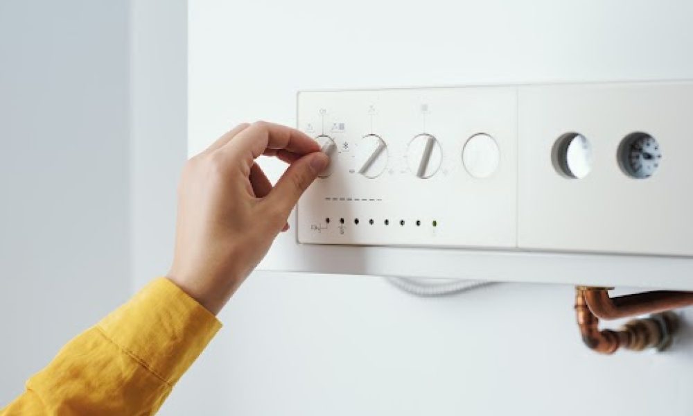Young woman checking settings and temperature on the boiler at home
